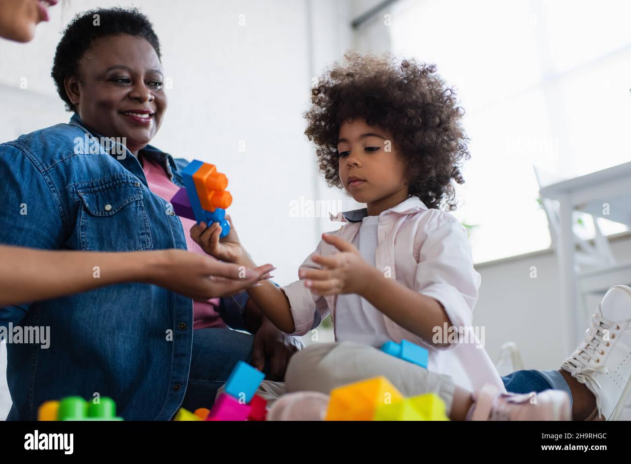 african american child holding building block while playing with mom and granny Stock Photo