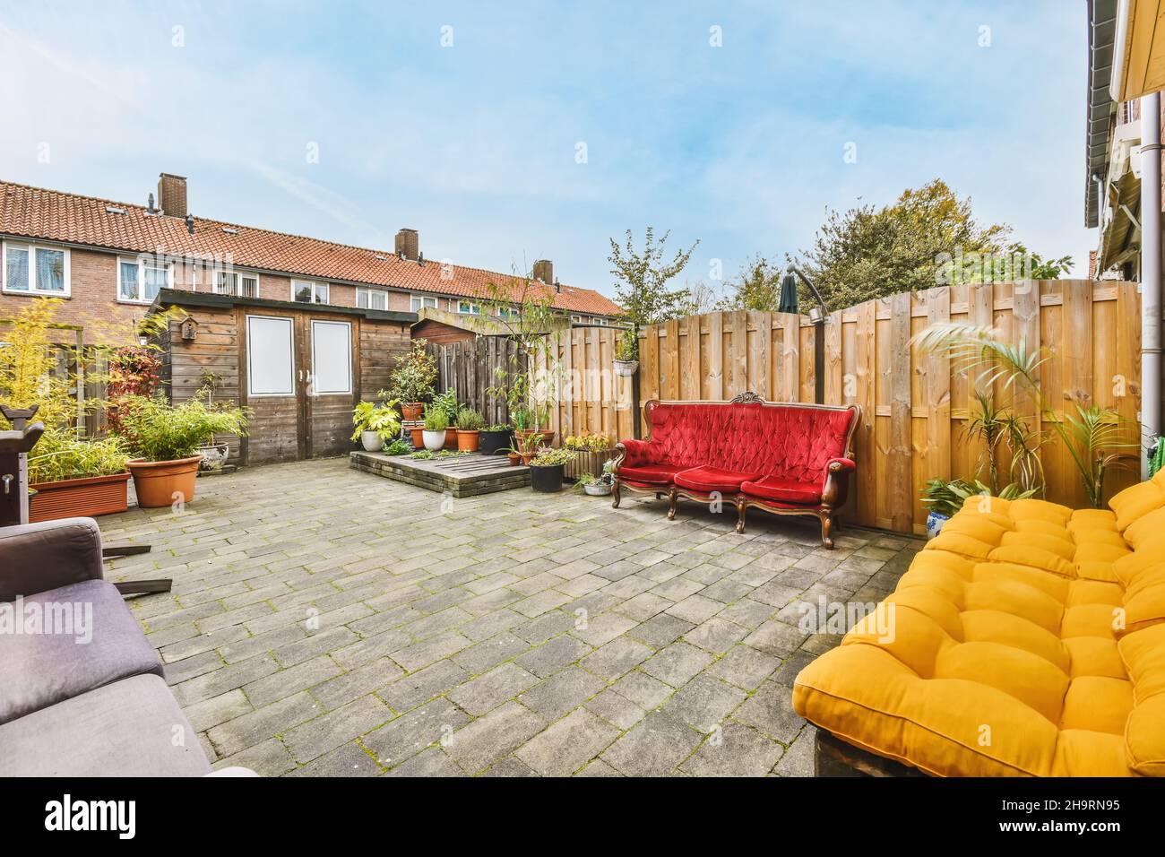 Cozy courtyard of a house with pots of flowers and a bright scarlet ...