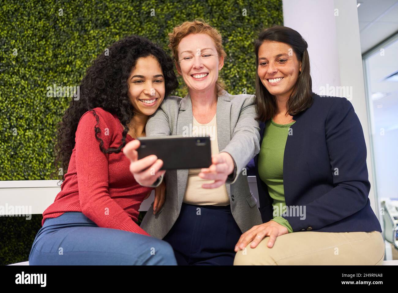 Three young women as friends with smartphones take a selfie for social media Stock Photo