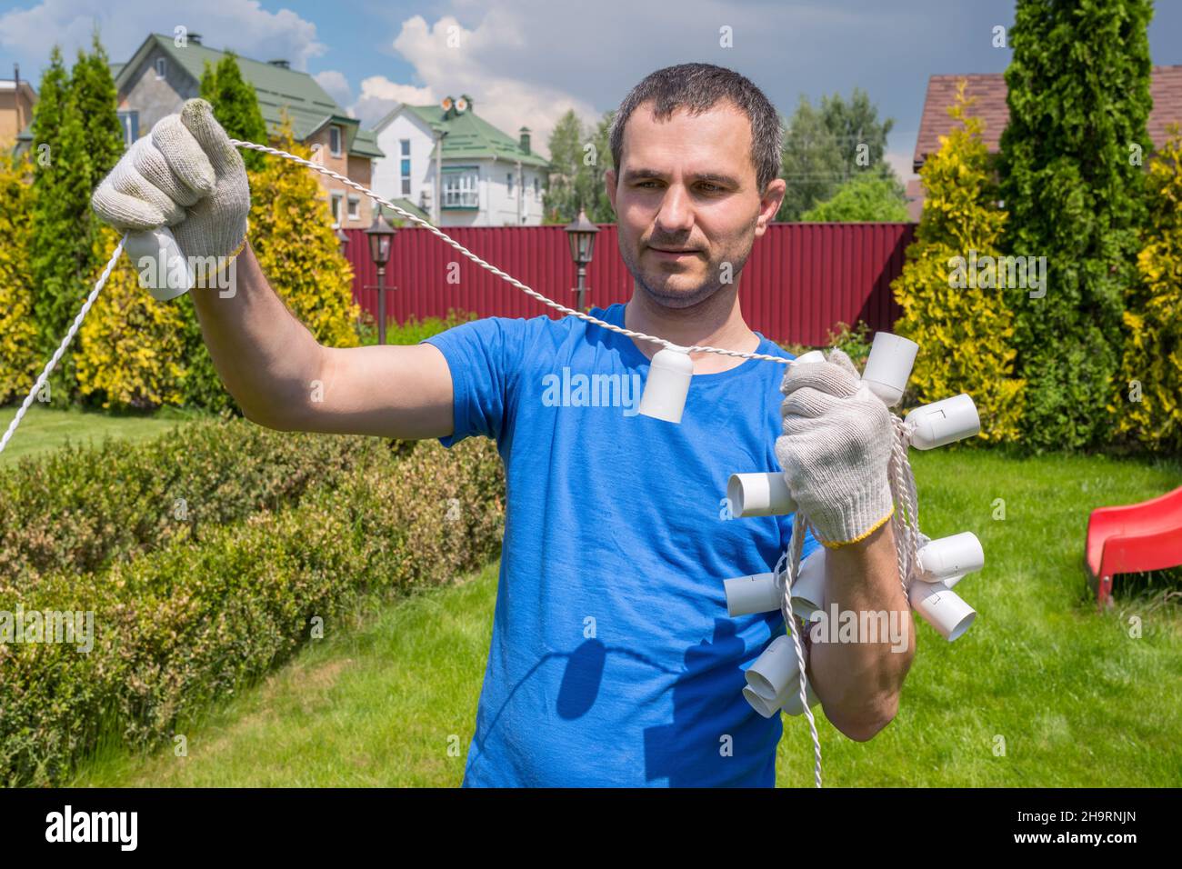 A man with an electric cable works in the garden. Backyard cleaning. Stock Photo