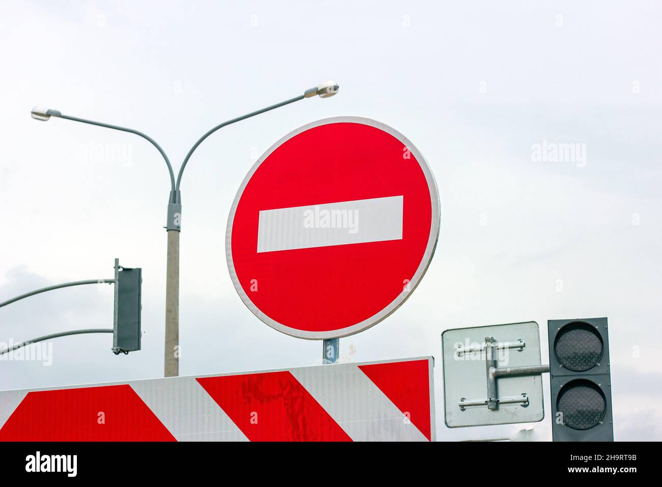Red and white Do not enter and other signs on gray dull overcast sky background. Stock Photo