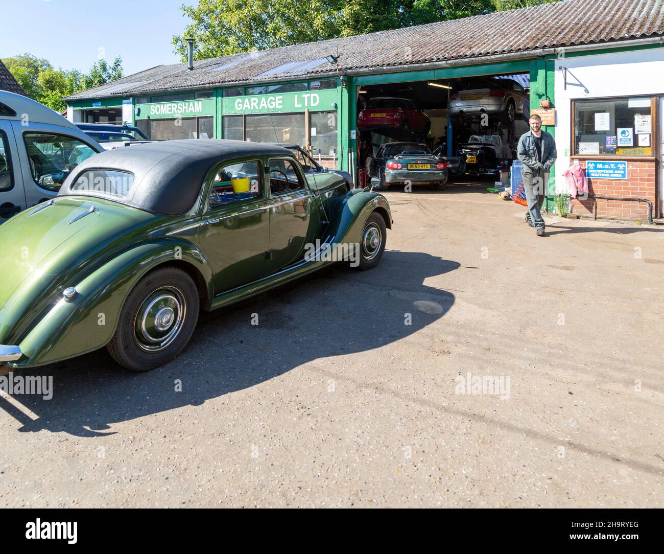 Classic vintage car on forecourt of village car mechanics garage, Somersham, Suffolk, England