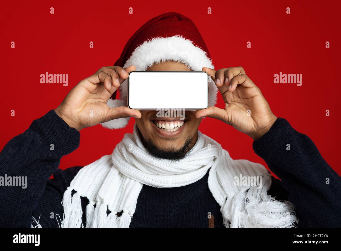 Cheerful african american man covering eyes with smartphone Stock Photo ...