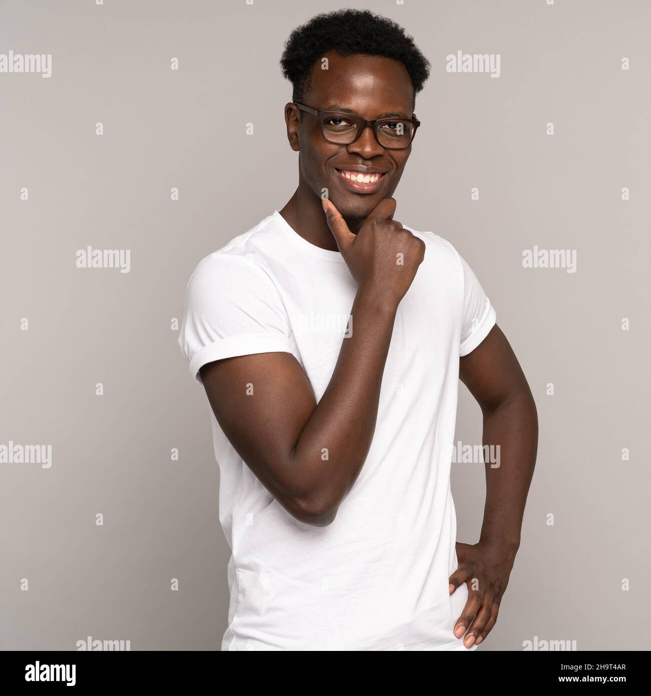 Confident happy african man millennial in white t-shirt with perfect toothy smile wearing eyeglasses Stock Photo