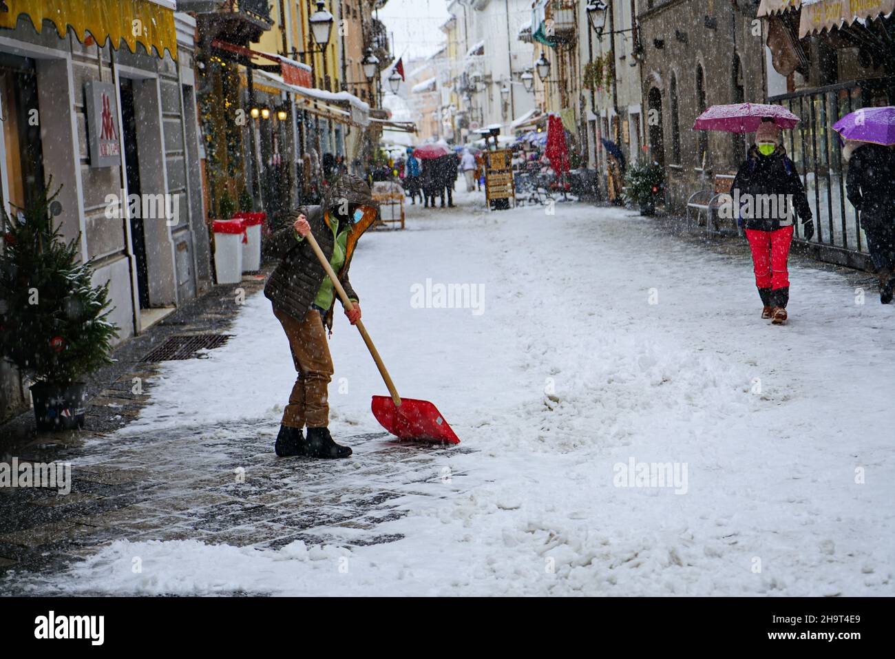 Man removing snow from a footpath after a snowstorm. Aosta, Italy -December 2021 Stock Photo