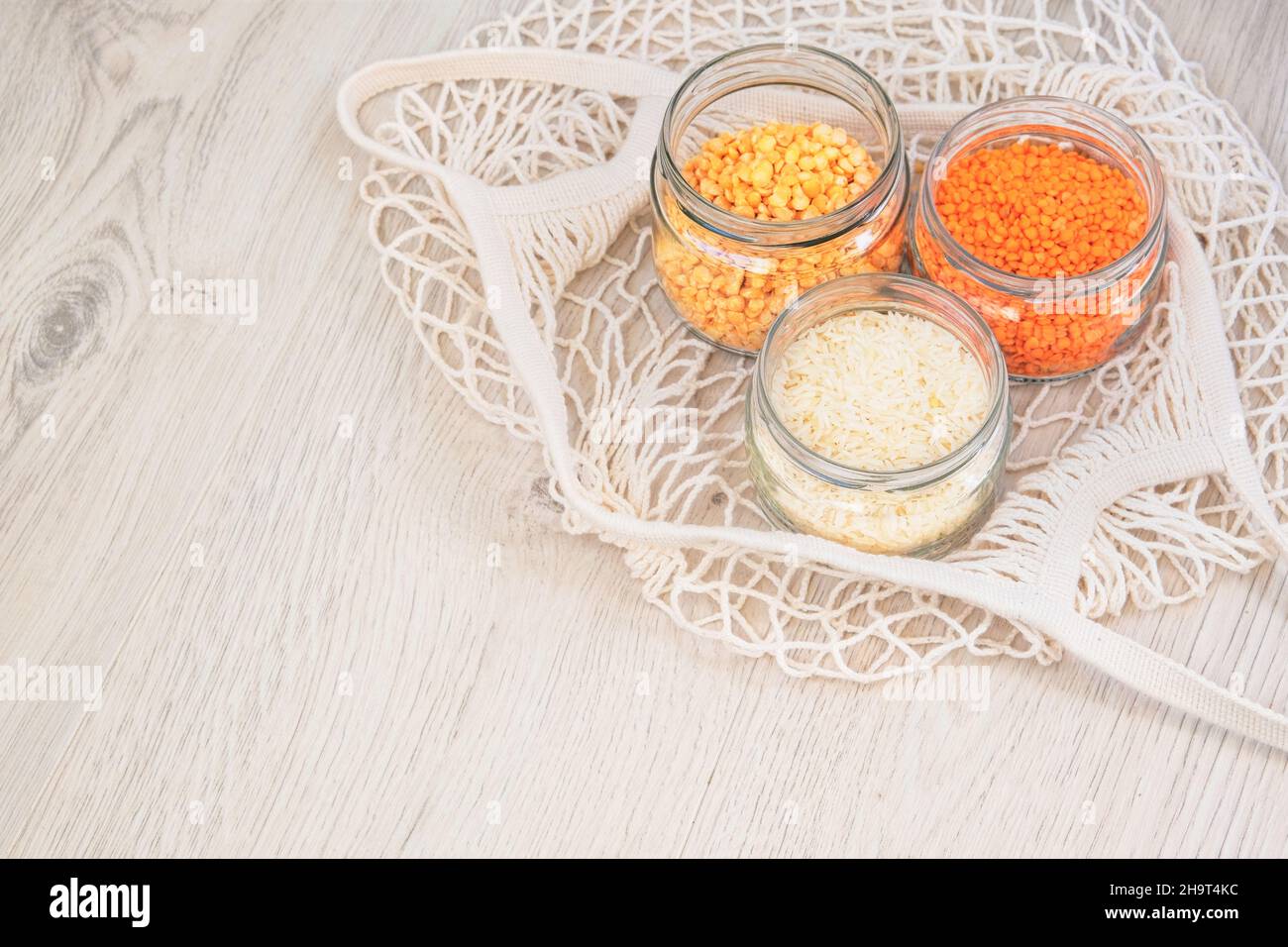Grains and cereals in zero waste shop. Foods storage in kitchen at low waste lifestyle. Lentils, peas and rice in glass jars on wooden background. Eco Stock Photo