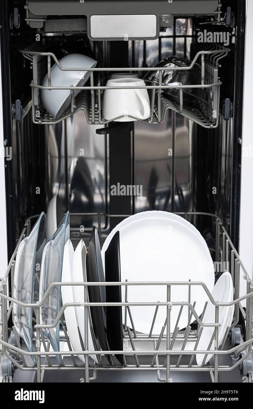 Clean plates after washing in dishwasher at home.  Modern kitchen with dishwashing machine. Household equipment. Stock Photo