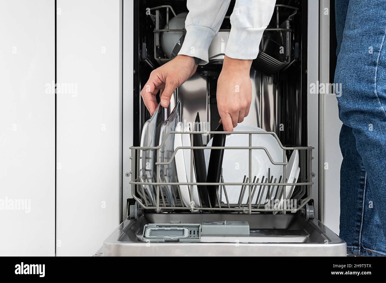 Woman doing dishes in dishwasher at home. Clean plates after washing