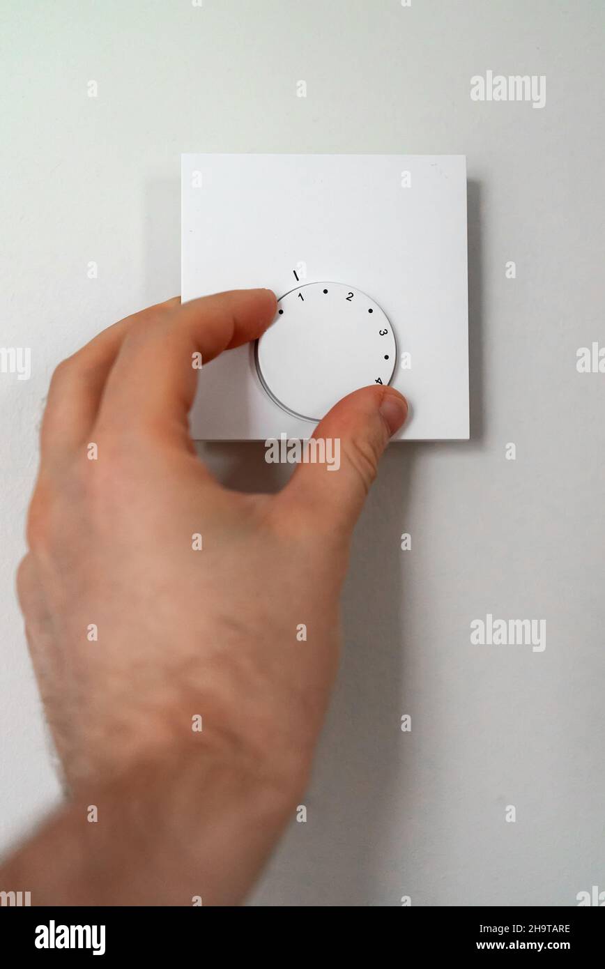 Man turning on heating thermostat to get warm Stock Photo Alamy
