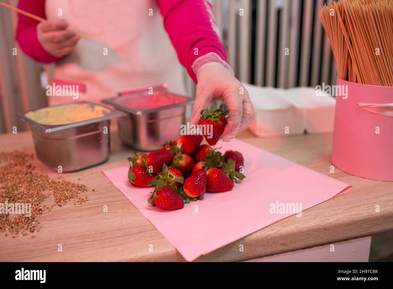 The pastry chef girl chooses strawberries for her cooking. chocolate-covered strawberries. Dipping in chocolate icing. Stock Photo