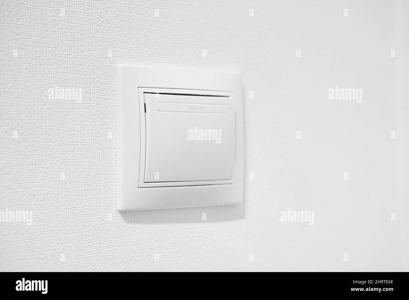 Standart rocker switch for exhaust fan or lighting applications. White common toggle switch in home. Inexpensive plastic push button switch against Stock Photo