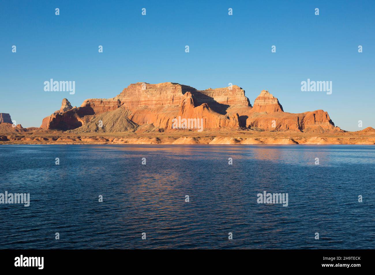 Glen Canyon National Recreation Area, Utah, USA. View across the tranquil waters of Lake Powell to high sandstone mesa, early morning. Stock Photo