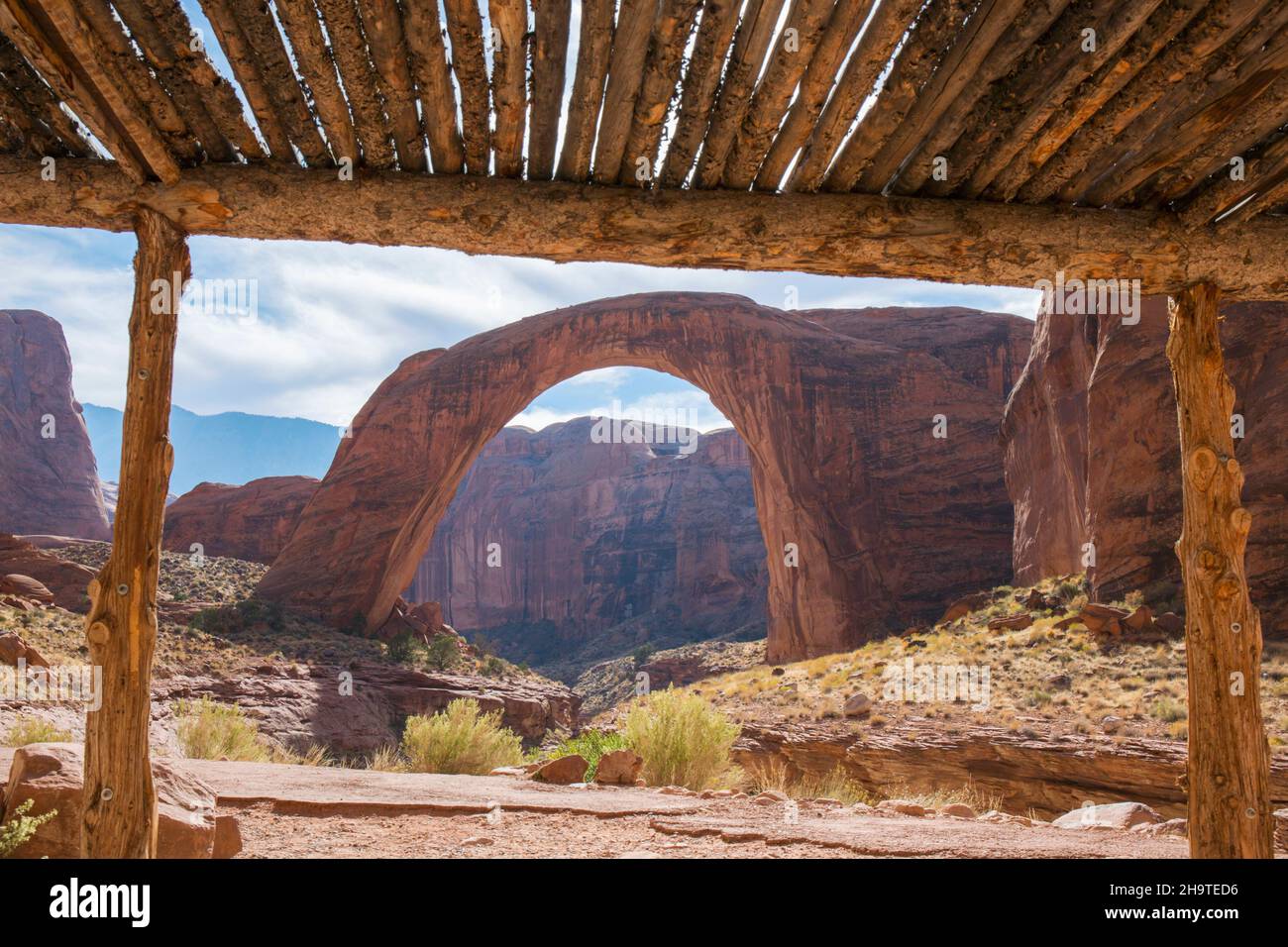 Glen Canyon National Recreation Area, Utah, USA. The huge sandstone arch of Rainbow Bridge National Monument framed by wooden shelter. Stock Photo