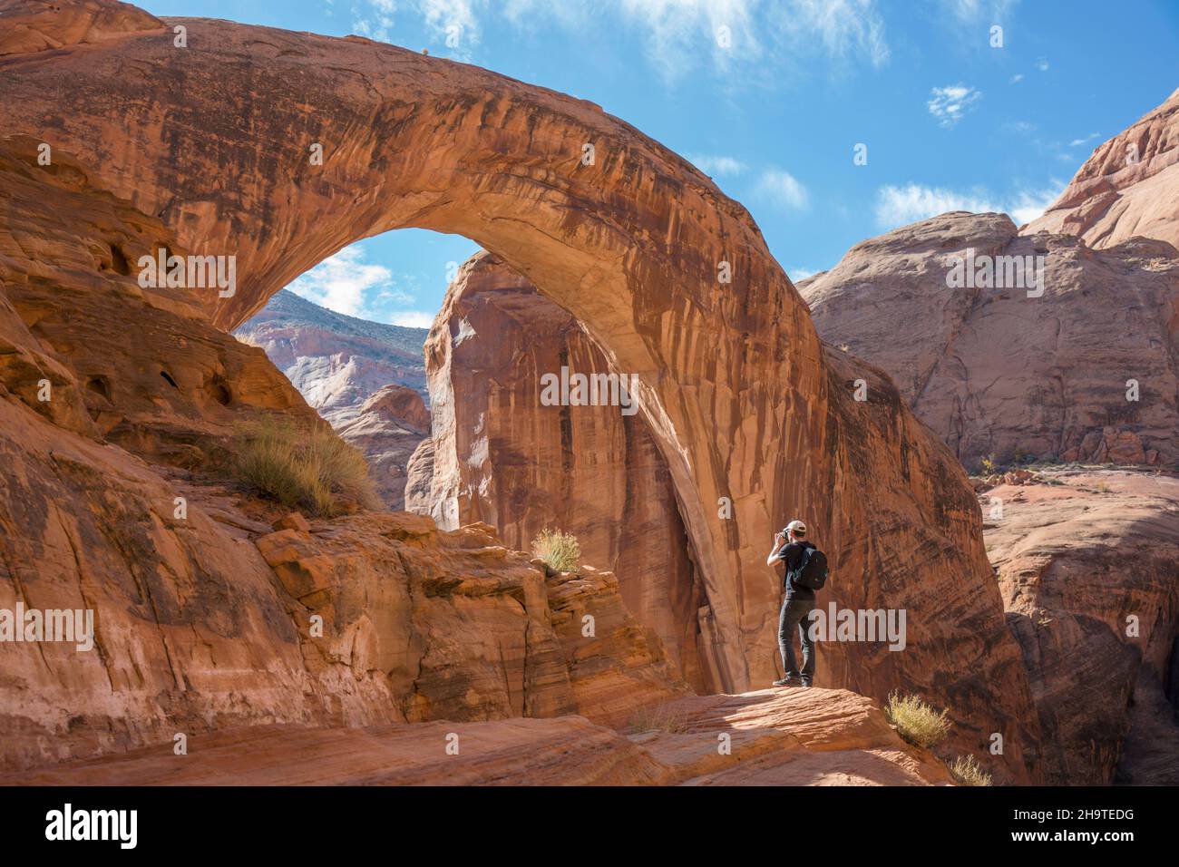 Glen Canyon National Recreation Area, Utah, USA. Photographer shooting backlit view of the huge sandstone arch of Rainbow Bridge National Monument. Stock Photo