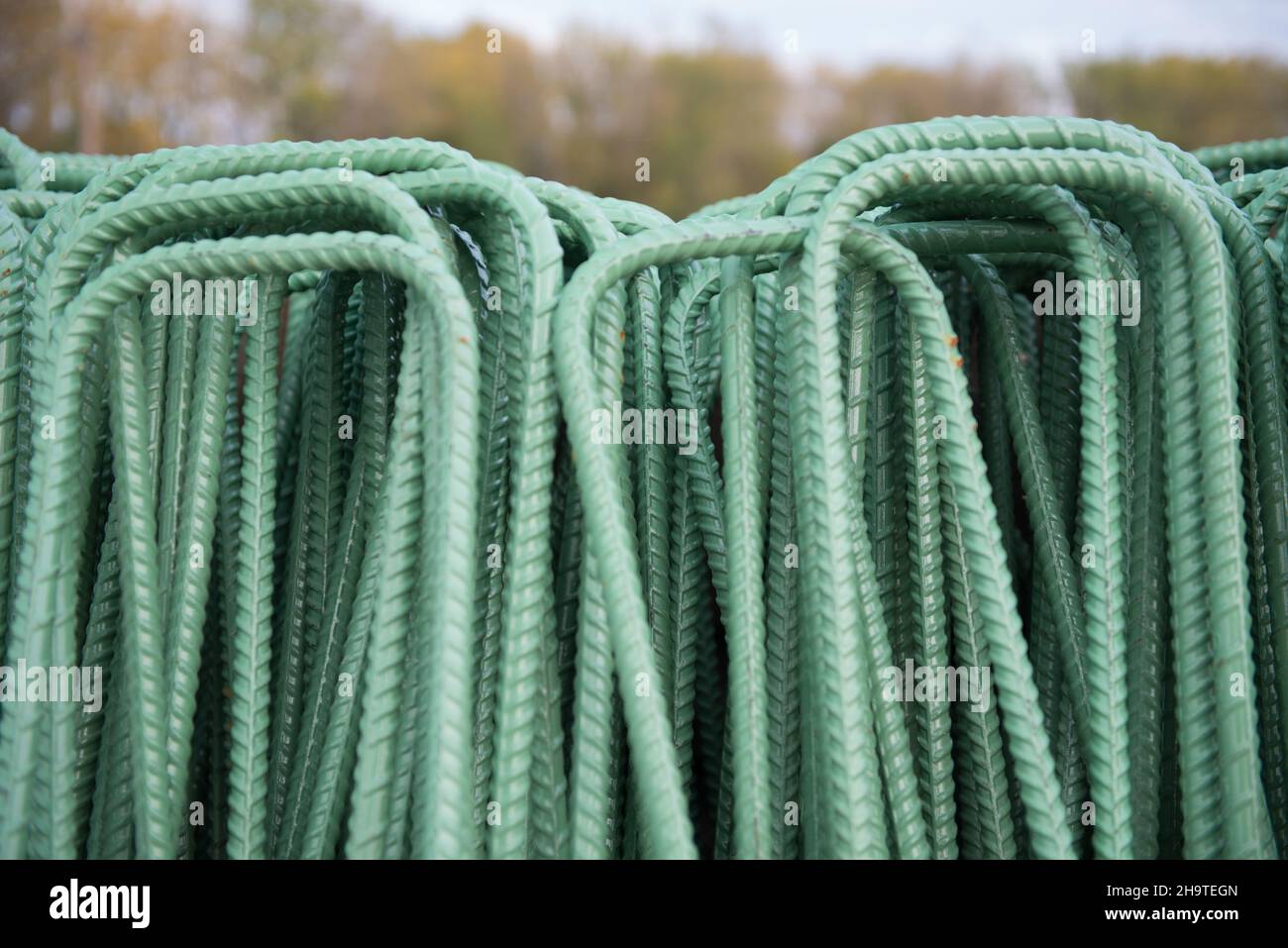A pile of per-fabricated rebar with a green epoxy coating for corrosion resistance is ready for installation at an infrastructure project. Stock Photo