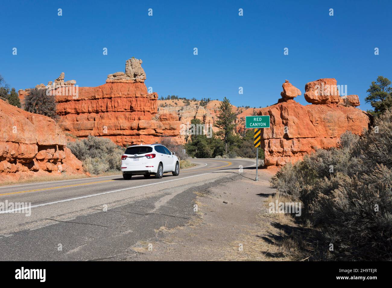 Dixie National Forest, Panguitch, Utah, USA. White car on Utah State Route 12 passing road sign marking the entrance to Red Canyon. Stock Photo