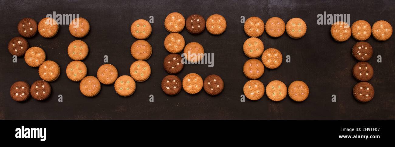 Panoramic image of some different cookies writting the word 'sweet' on a black wooden surface Stock Photo