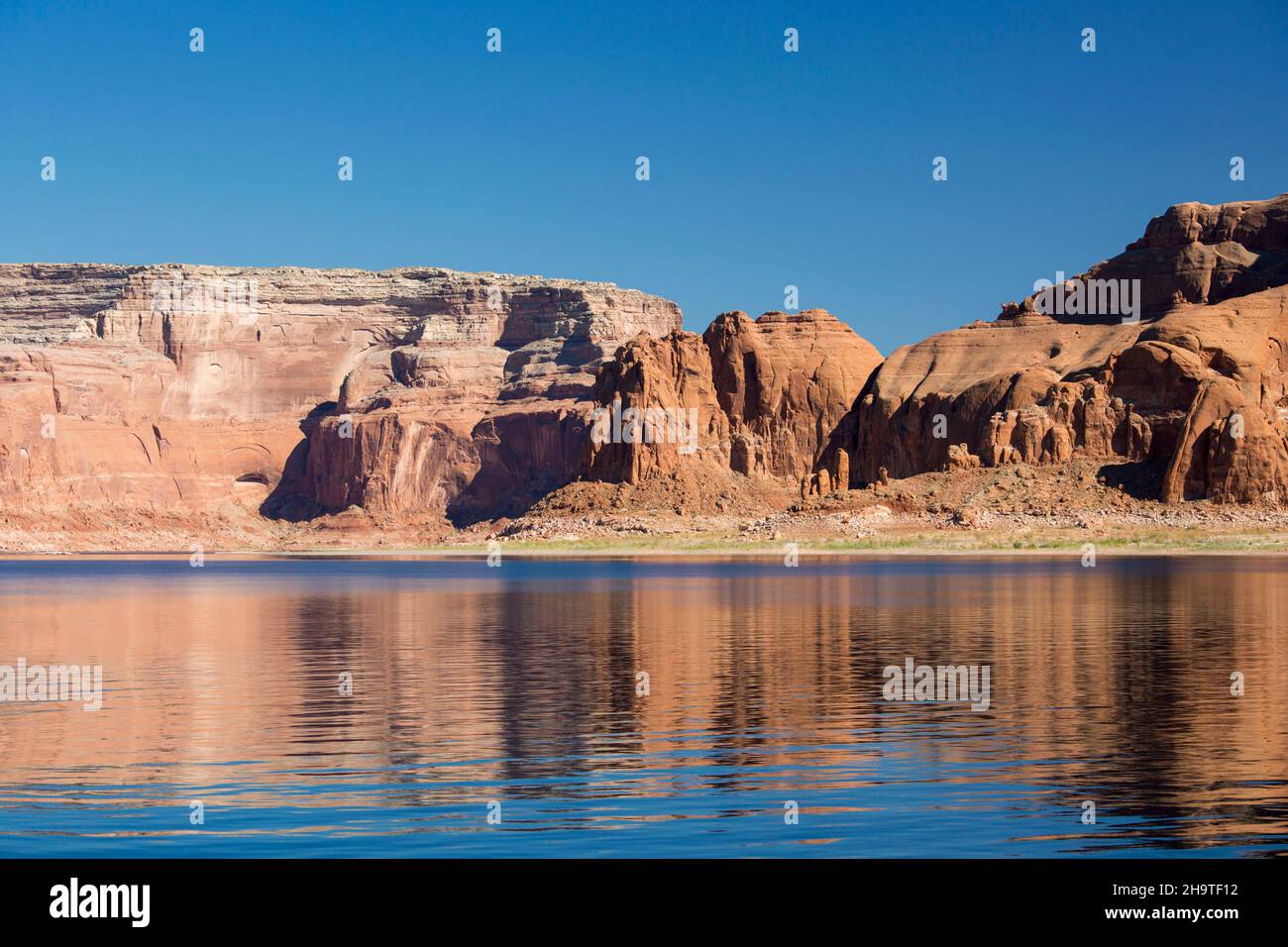Glen Canyon National Recreation Area, Utah, USA. High red sandstone cliffs reflected in the tranquil waters of Lake Powell. Stock Photo