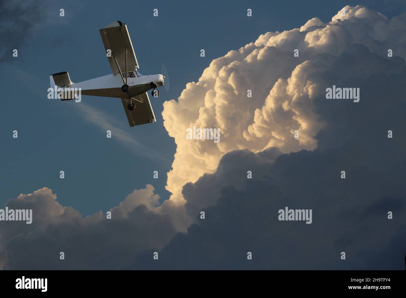 Small single-engine airplane against the background of the cloudy sky. Stock Photo