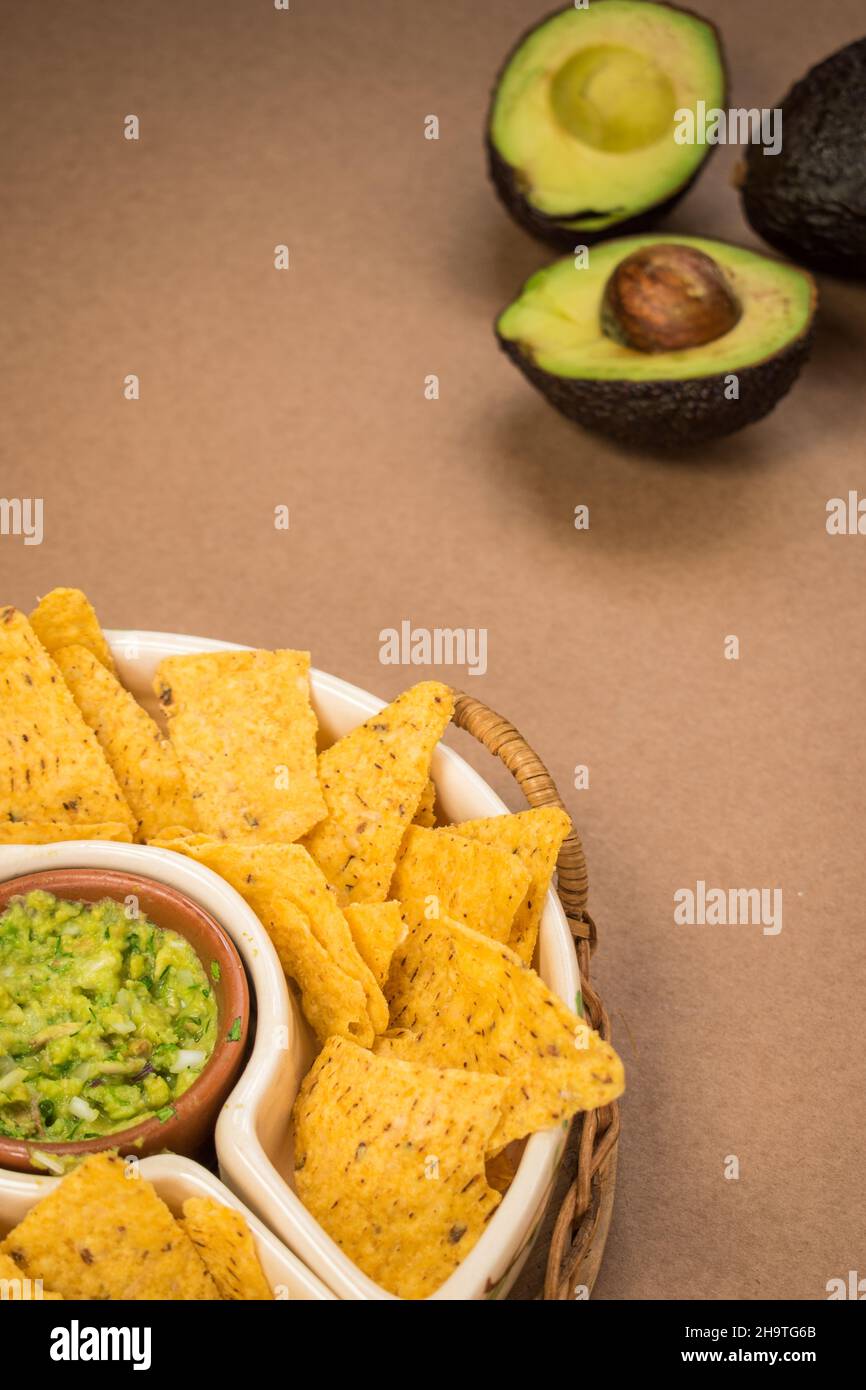 Some fried nachos in a pot with some fresh guacamole on a green surface Stock Photo