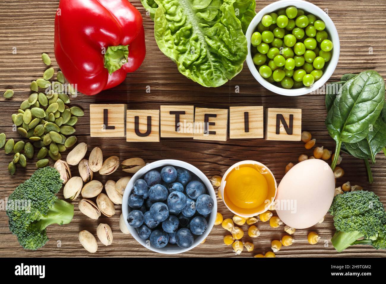 Food sources of lutein and zeaxanthin. Foods as yolk egg, broccoli, pumpkin seeds, pepper, lettuce, green peas, spinach, blueberries, corn and pistach Stock Photo