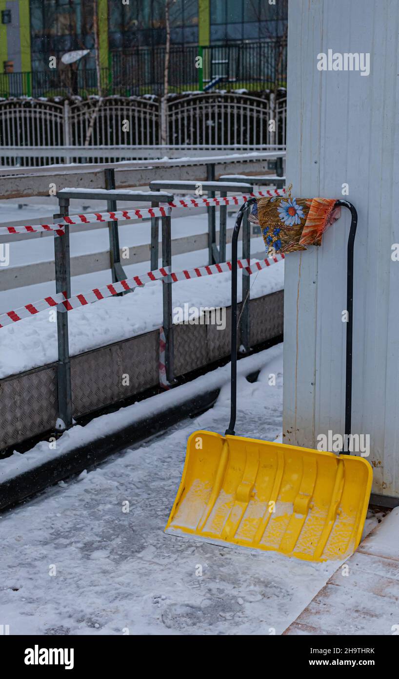 yellow snow shovel stands against the wall Stock Photo