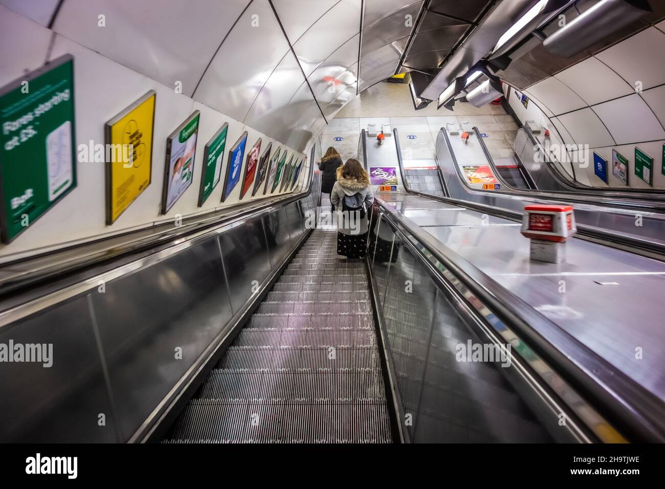 View from above looking down an escalator at London Bridge underground station with two passengers at the bottom, taken on the 12th December 2020 Stock Photo