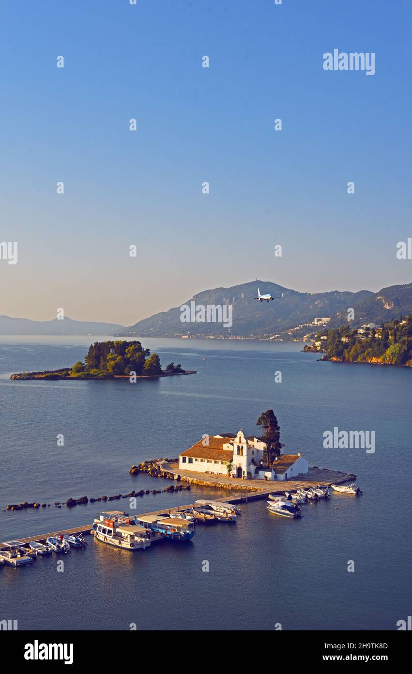 Vlacherna Monastery in the middle of a bay, in the background an aircraft approaching for landing, Greece, Ionian Islands, Corfu, Kerkira Stock Photo