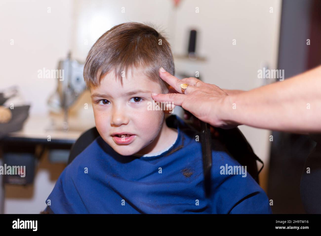 Boy is having a home haircut in home maide sewing room. living at home