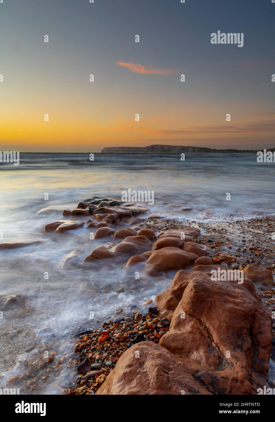 sunset over the sea and rocks at compton bay on the coastline of the isle of wight, shoreline of the isle of wight at compton bay at sun down, moody. Stock Photo