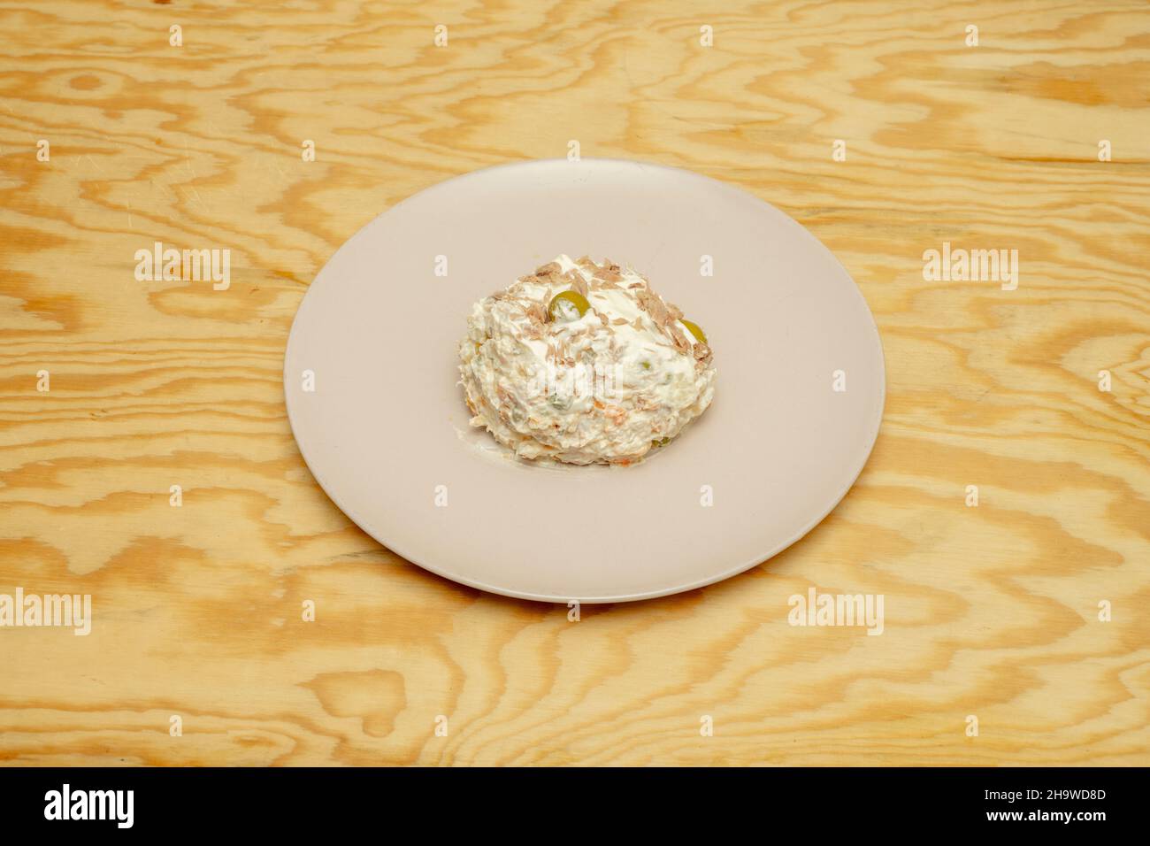 Ration of Russian salad with mayonnaise, cooked potato and canned tuna with olives and carrots to serve as tapas in a restaurant Stock Photo