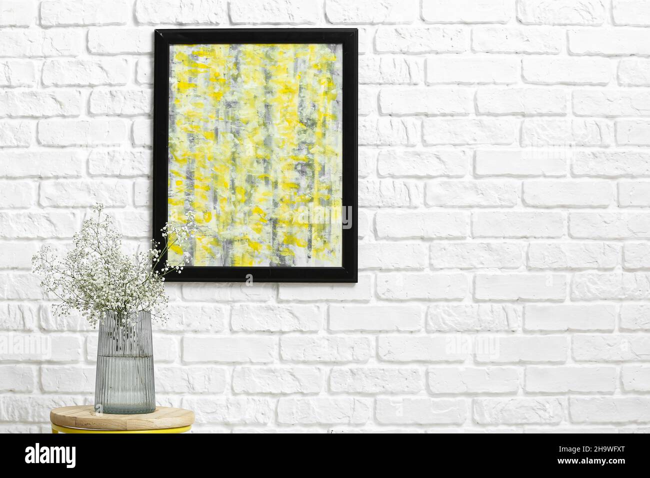 Vase with beautiful gypsophila flowers on table near white brick wall ...