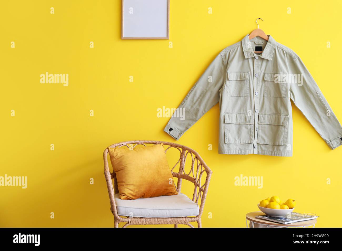 Comfortable chair and stylish jacket hanging on color wall in room Stock Photo