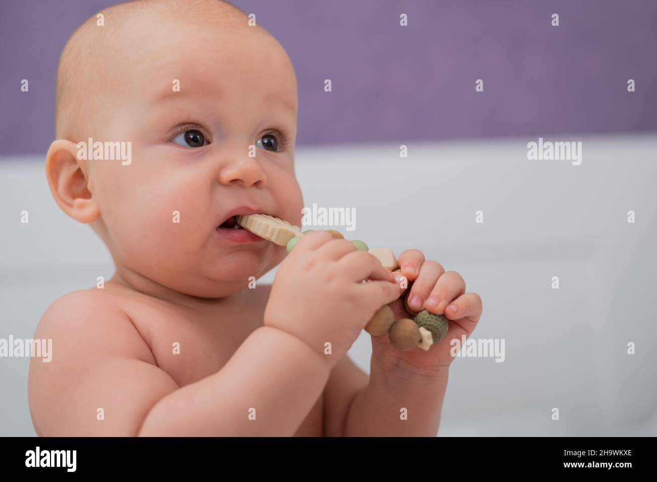 Baby boy gnaws wooden teething boxes. Eco friendly toy. Stock Photo