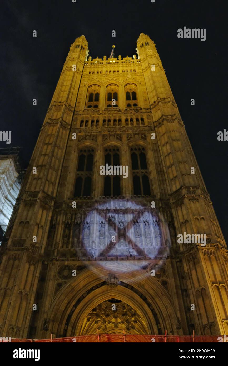 London, UK, 8th Dec, 2021, An Extinction Rebellion logo is projected onto the Houses of Parliament as the third reading of the Police, Crime, Sentencing and Courts Bill (PCSC) got underway in the House of Lords. The new legislation, if passed, will grant police additional powers to crack-down on protest by allowing stop-and-search of activists and the breaking-up of demonstrations deemed as causing 'serious annoyance'. Credit: Eleventh Hour Photography/Alamy Live News Stock Photo