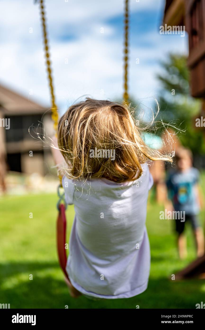 Young Caucasian girl on a swing with long blond hair blowing in the ...