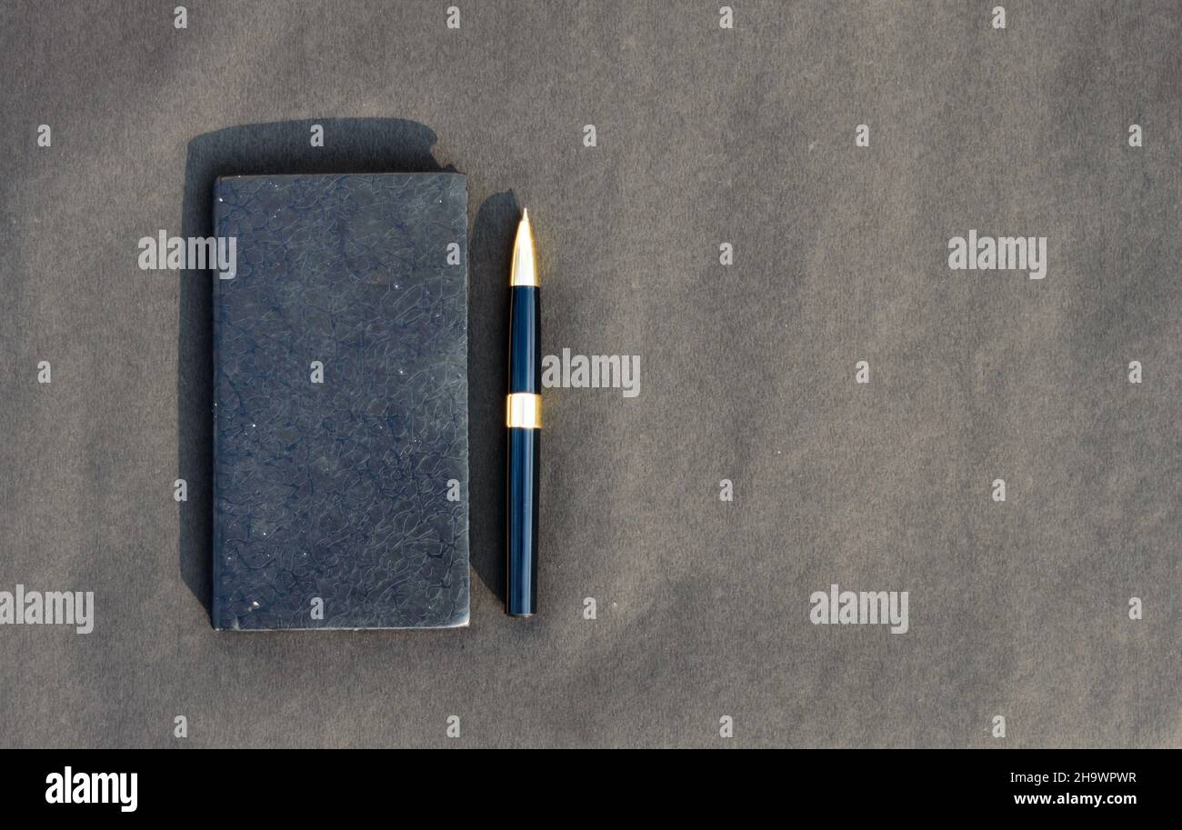 Pen placed on notebook on black background. High angle view. Copy space room for text. Stock Photo