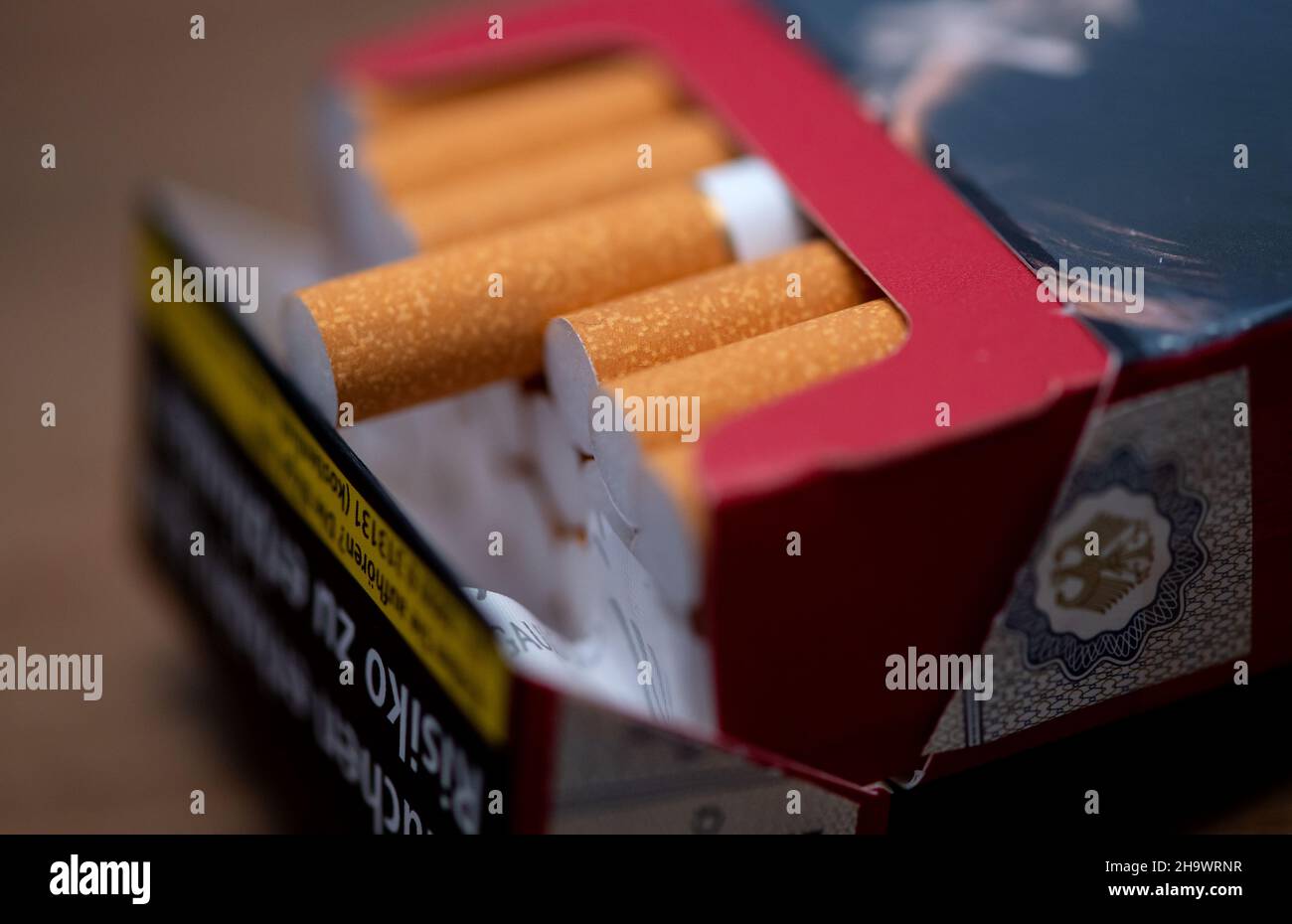 Munich, Germany. 08th Dec, 2021. Cigarettes lying on a table. The German consumer association Pro Rauchfrei sues the operator of two Munich supermarkets for injunctive relief. At the checkouts, cigarettes are offered via vending machines without health-related warnings being visible to the customer from the outside. Credit: Sven Hoppe/dpa/Alamy Live News Stock Photo