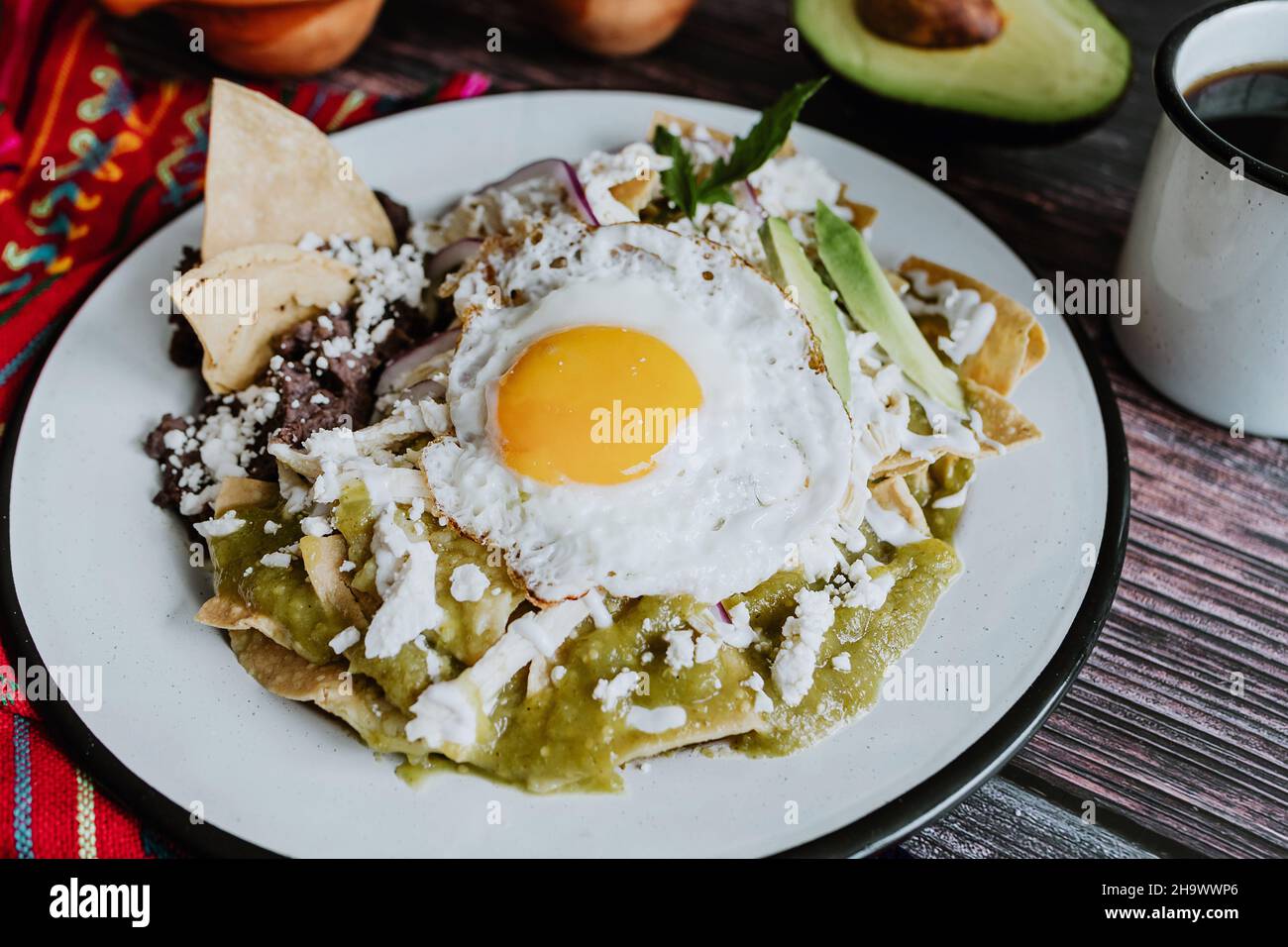 Mexican green chilaquiles with fried egg, chicken and spicy green sauce traditional breakfast in