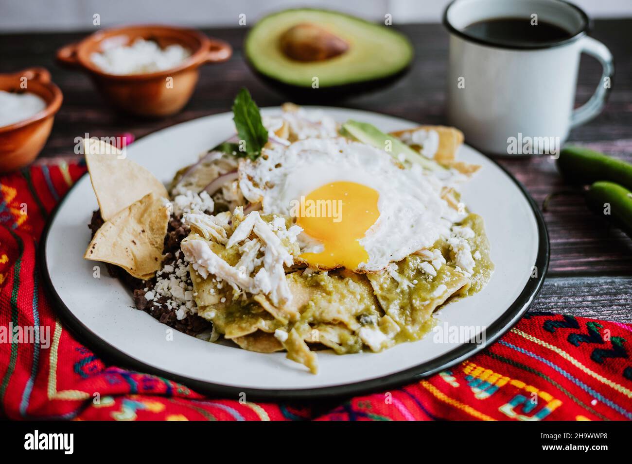 Mexican green chilaquiles with fried egg, chicken and spicy green sauce traditional breakfast in
