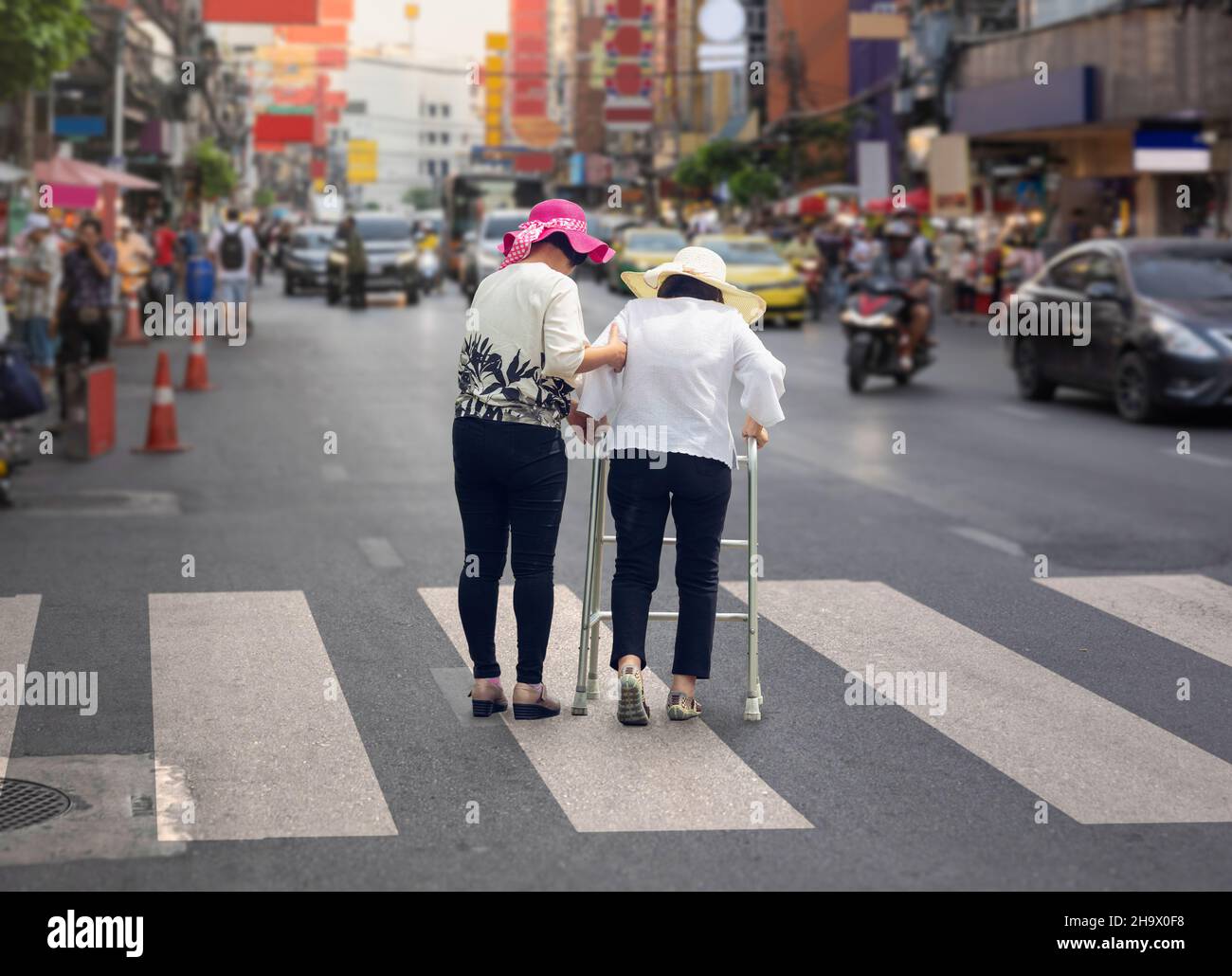Daughter take care elderly woman crossing the street in Chinatown area Stock Photo