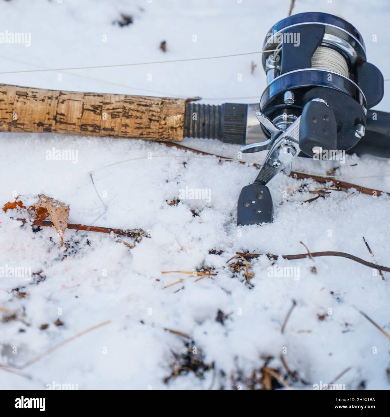 Spinning rod with baitcasting reel lying on the snow in the winter Stock Photo