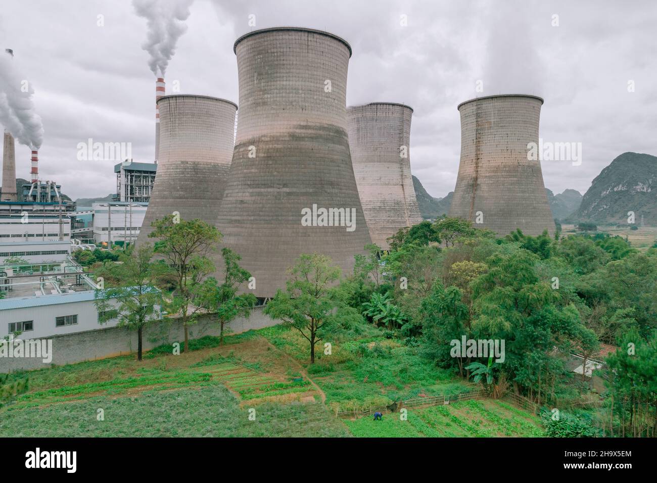 The cooling tower of the factory built next to the green space Stock Photo