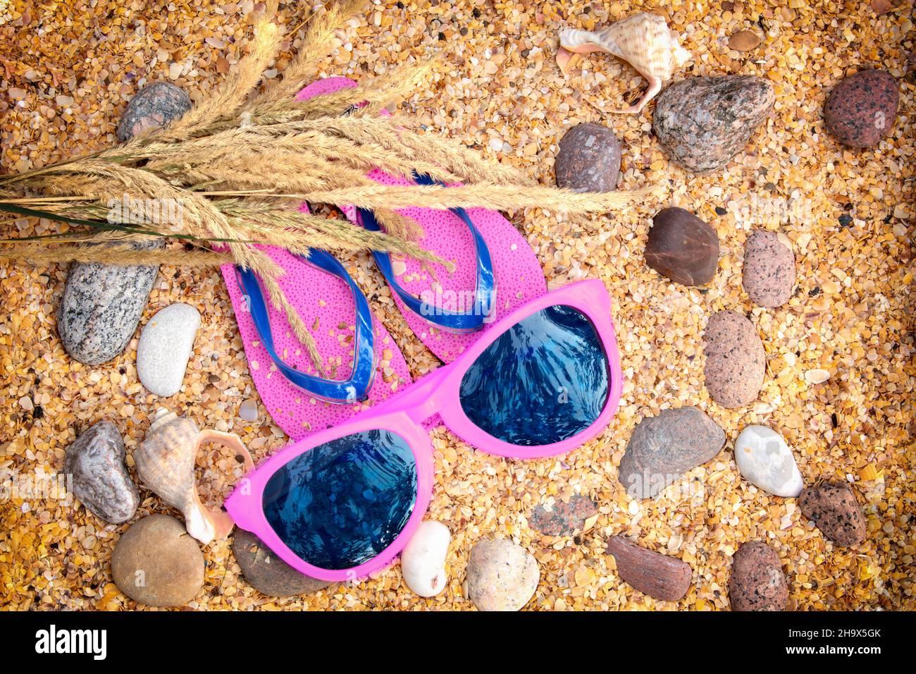 Beach scene. Sun straw hat, a pair of flip flop sandals, and sunglasses ...