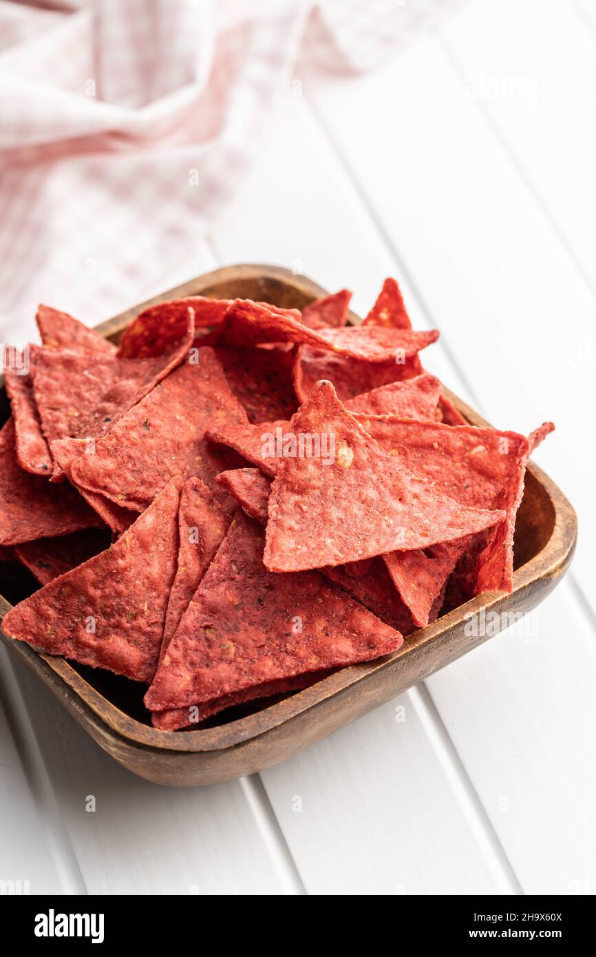 Salted tortilla chips triangle with red beet flavor in bowl on white