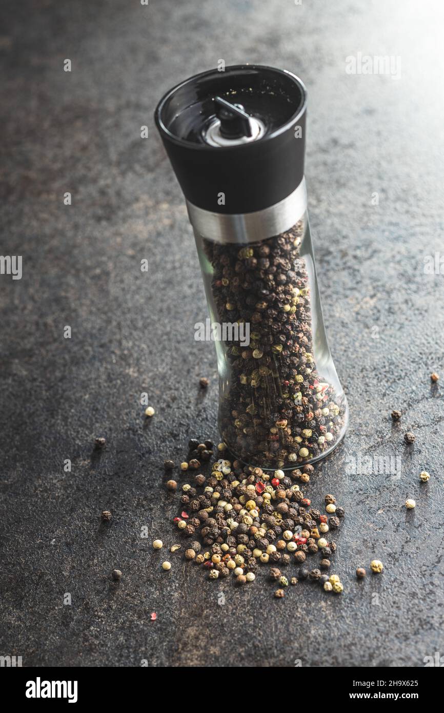https://c8.alamy.com/comp/2H9X625/pepper-mill-and-whole-pepper-on-black-table-2H9X625.jpg