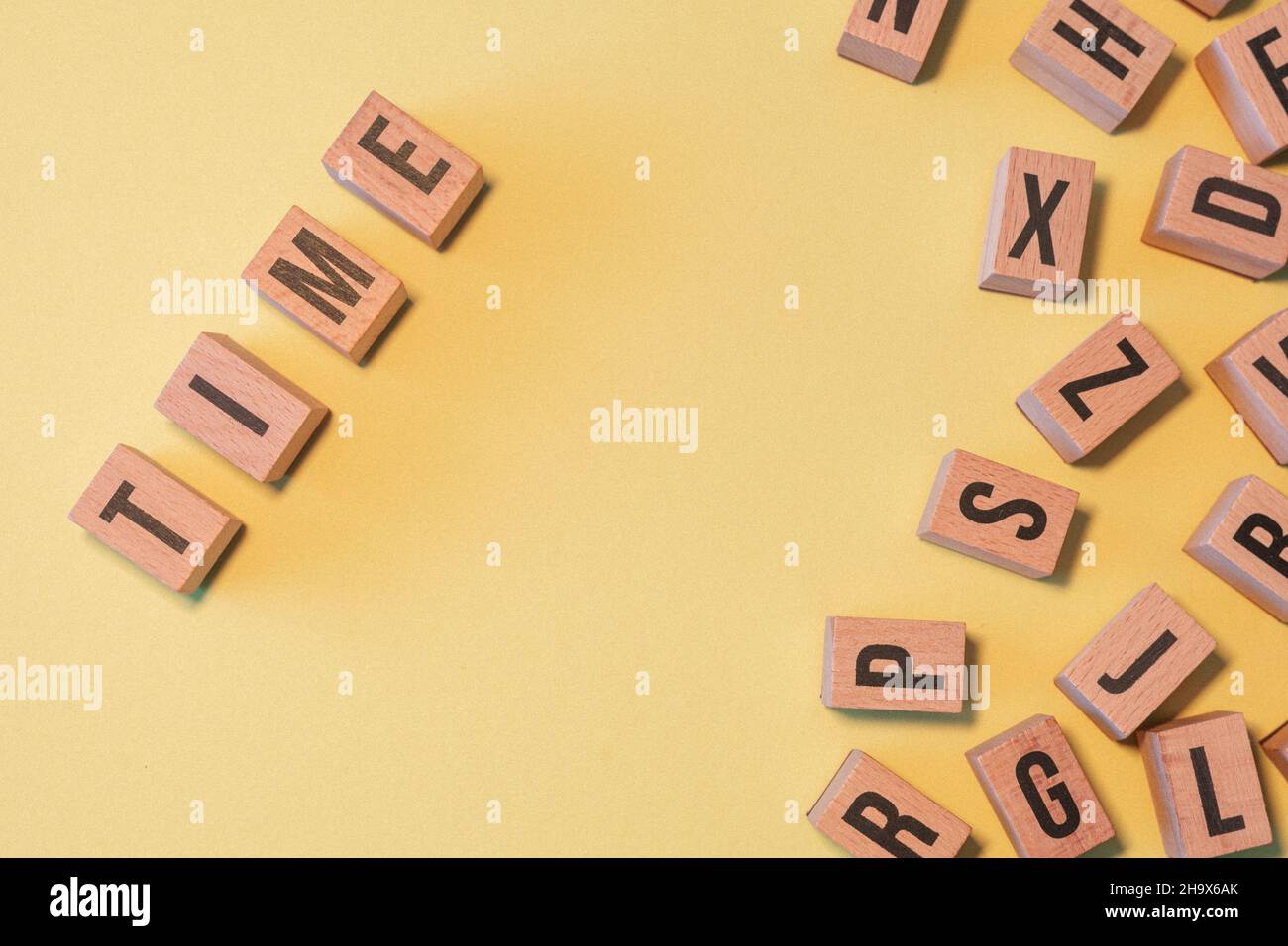 Word TIME, taken from a pile of wooden letter blocks with yellow ...