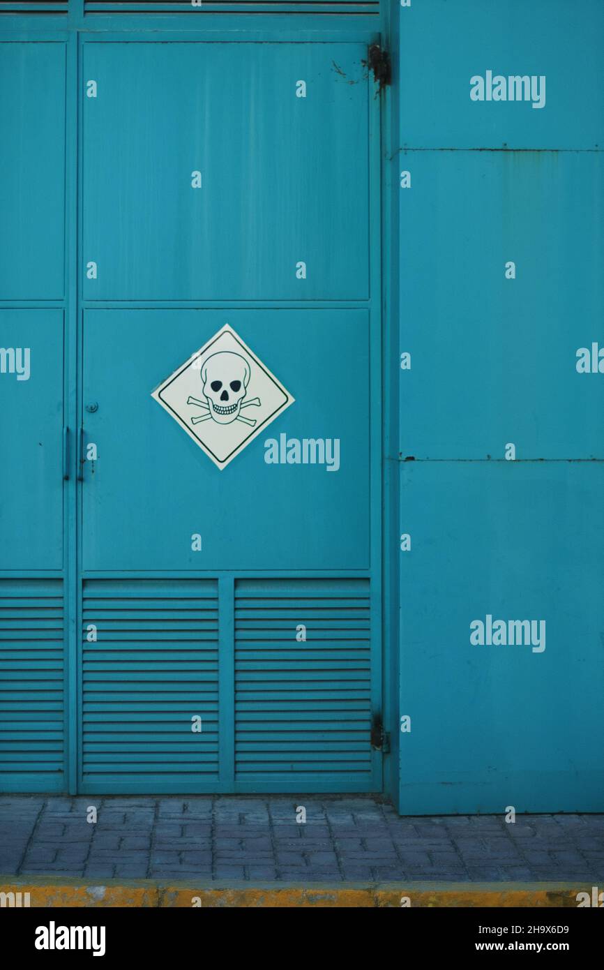 Turquoise colored Industrial Door with a danger sign with a skull. Stock Photo