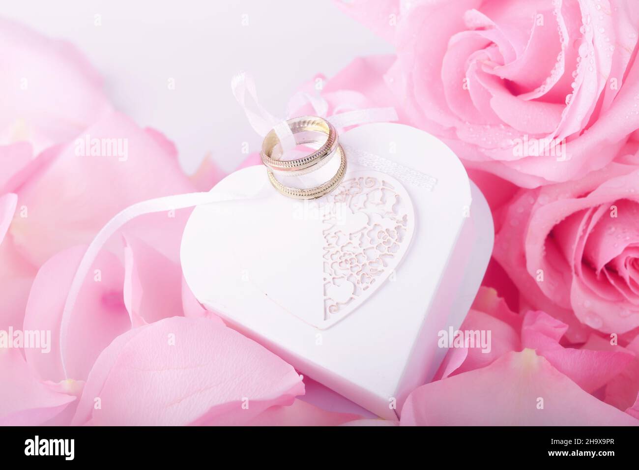 pink roses and heart-shaped box wedding rings. gentle love background for valentines day Stock Photo