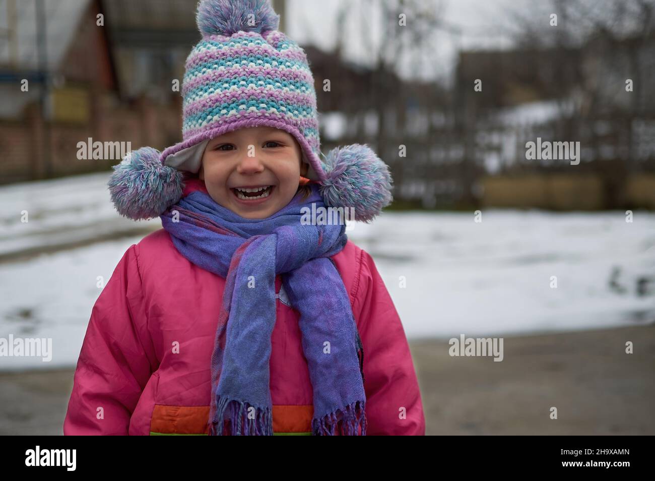 small toddler girl smiling in winter outdoor with Rainbow Hat and muffler Stock Photo